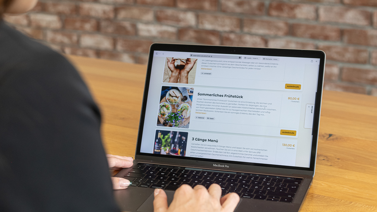 Eine Frau sitzt an einem Laptop mit einem geöffneten DIRS21 Gutscheinshop